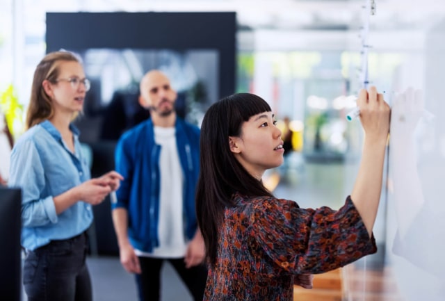 3 people working around a whiteboard generating ideas