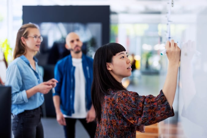 3 people working around a whiteboard generating ideas